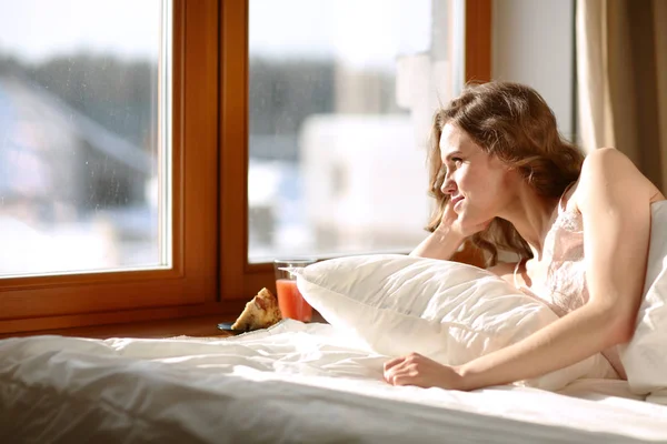 Nő az ágyban fekve, a kora reggeli órákban közelében ablak. — Stock Fotó