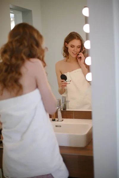 Jonge vrouw staande op badkamer met telefoon. — Stockfoto