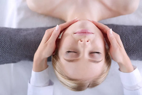 Jovem deitada em uma mesa de massagem, relaxando com os olhos fechados . — Fotografia de Stock