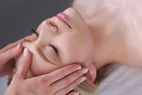 Ung kvinna liggande på en massagebänk, avkopplande med slutna ögon. — Stockfoto
