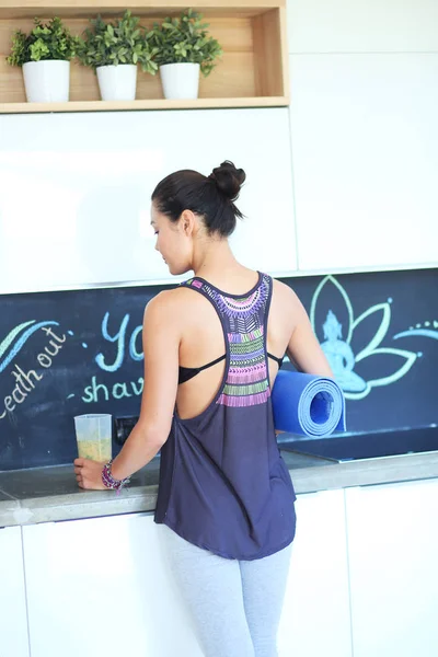 Retrato de mujer sonriente sosteniendo en su mano una esterilla de yoga mientras s — Foto de Stock