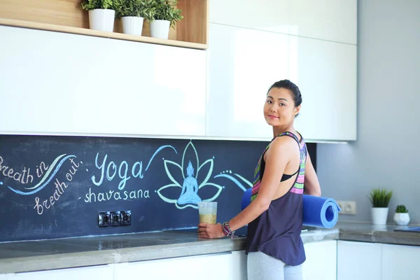 Retrato de mujer sonriente sosteniendo en su mano una esterilla de yoga mientras s — Foto de Stock