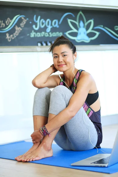 Portrait of smiling yoga woman sitting at yoga mat after workout