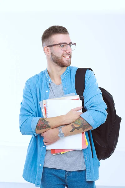Un estudiante masculino con una bolsa de la escuela sosteniendo libros aislados en blanco —  Fotos de Stock