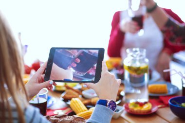 Ahşap masada otururken birlikte yemek yiyen bir grup insanın üst düzey görüntüsü. Masada yemek var. İnsanlar fast food yiyor..