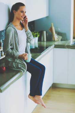 modern mutfakta otururken cep telefonu kullanan kadın.