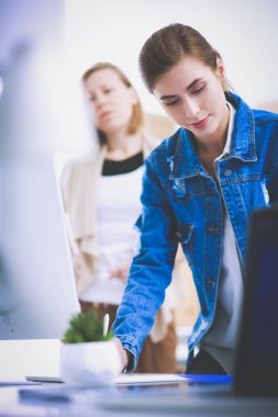 Masanın yanında duran iki genç kadın enstrüman, plan ve dizüstü bilgisayarla.