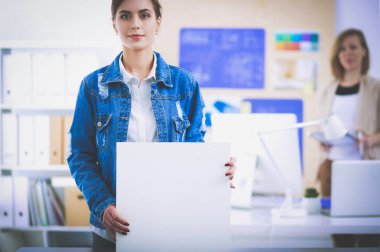 Masanın yanında duran iki genç kadın enstrüman, plan ve dizüstü bilgisayarla.