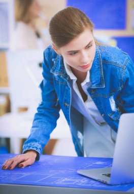 Masanın yanında duran iki genç kadın enstrüman, plan ve dizüstü bilgisayarla.