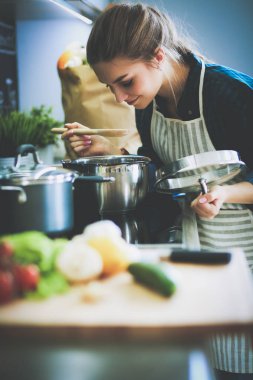 Mutfakta sobanın yanında duran genç bir kadın. .