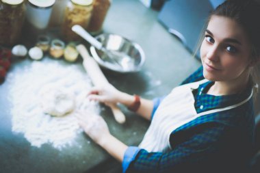 Mutfakta sobanın yanında duran genç bir kadın. .