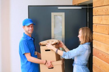 Mavi üniformalı gülümseyen kurye servis konseptine paket kutusu teslim eden teslimatçı.