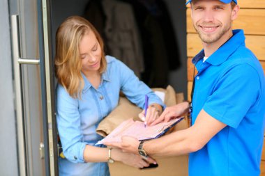 Mavi üniformalı gülümseyen kurye servis konseptine paket kutusu teslim eden teslimatçı.