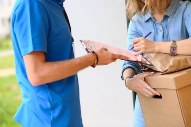 Mavi üniformalı gülümseyen kurye servis konseptine paket kutusu teslim eden teslimatçı.