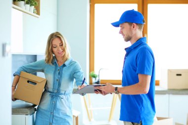 Mavi üniformalı gülümseyen kurye servis konseptine paket kutusu teslim eden teslimatçı.