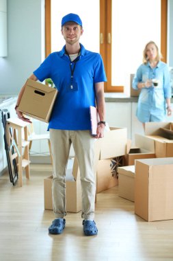 Mavi üniformalı gülümseyen kurye servis konseptine paket kutusu teslim eden teslimatçı.