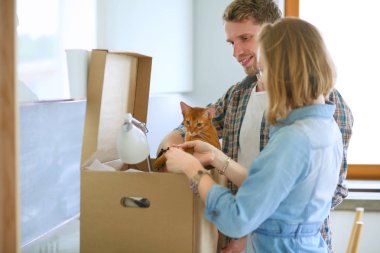 Genç bir çift yeni evinde büyük bir karton kutu taşıyor. Taşınıyorlar.