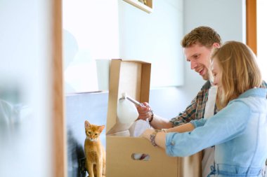Genç bir çift yeni evinde büyük bir karton kutu taşıyor. Taşınıyorlar.