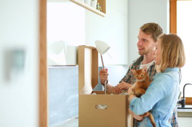 Genç bir çift yeni evinde büyük bir karton kutu taşıyor. Taşınıyorlar.