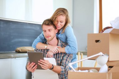 Genç bir çift yeni ev içinde hareket. Oturma ve açma sonra rahatlatıcı. Bir şey üstünde laptop arıyorum