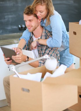 Genç bir çift yeni ev içinde hareket. Oturma ve açma sonra rahatlatıcı. Bir şey üstünde laptop arıyorum