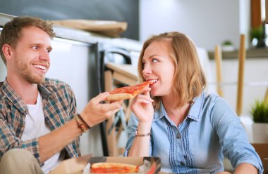 Genç bir çift var bir pizza öğle yemeği kırılmak yere çevrelerindeki kutuları ile yeni evine taşıdıktan sonra