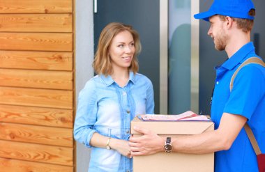 Mavi üniformalı gülümseyen kurye servis konseptine paket kutusu teslim eden teslimatçı.