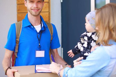 Mavi üniformalı gülümseyen kurye servis konseptine paket kutusu teslim eden teslimatçı.