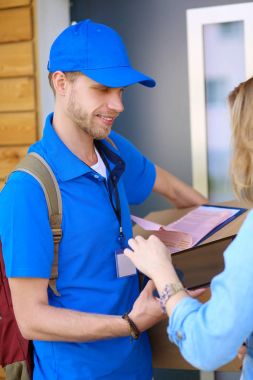 Mavi üniformalı gülümseyen kurye servis konseptine paket kutusu teslim eden teslimatçı.