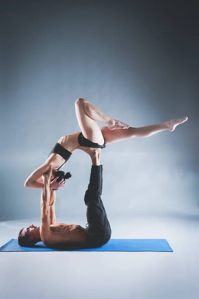 Young couple practicing acro yoga on mat in studio together. Acroyoga. Couple yoga. Partner yoga.