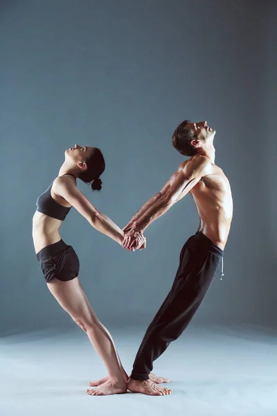 Young couple practicing acro yoga on mat in studio together. Acroyoga. Couple yoga. Partner yoga.