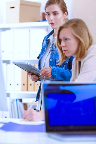 Two young woman standing near desk with instruments, plan and laptop. — Stock Photo, Image