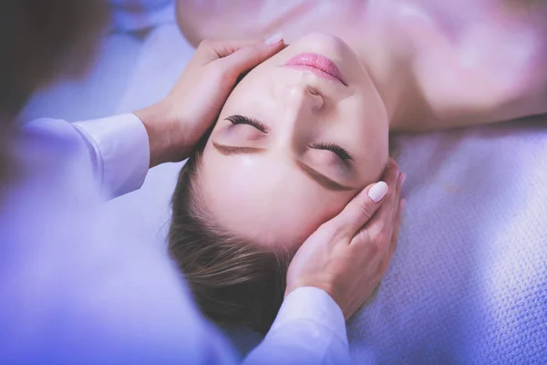 Mujer joven acostada en una mesa de masaje, relajándose con los ojos cerrados. Una mujer. Salón de spa — Foto de Stock