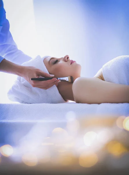 Mujer joven acostada en una mesa de masaje, relajándose con los ojos cerrados. Una mujer. Salón de spa —  Fotos de Stock