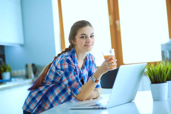 Schöne junge lächelnde Ärztin sitzt am Schreibtisch und schreibt. — Stockfoto