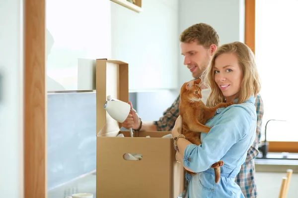 Casal jovem carregando caixa de papelão grande em casa nova. — Fotografia de Stock