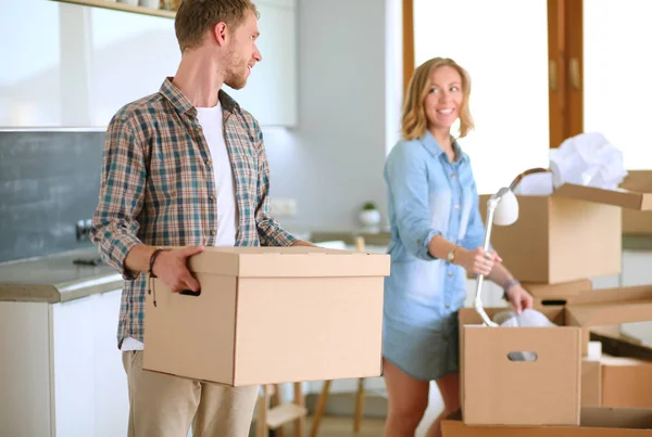 Genç bir çift yeni evinde büyük bir karton kutu taşıyor. Taşınıyorlar. — Stok fotoğraf