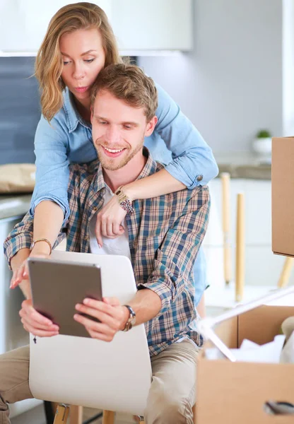 Unga par som flyttar i nya hem. Sitter och avkopplande efter uppackning. Ser något på laptop — Stockfoto