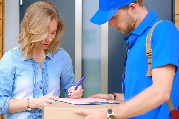 Leende leverans man i blå uniform leverera paket låda till mottagaren - kurir service koncept — Stockfoto