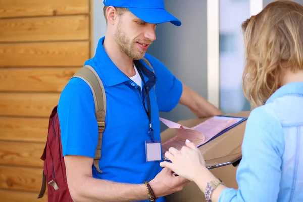 Leende leverans man i blå uniform leverera paket låda till mottagaren - kurir service koncept — Stockfoto