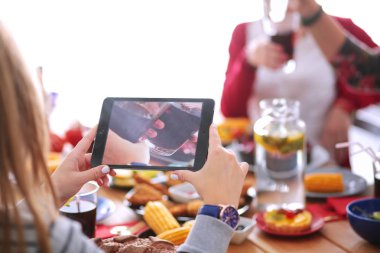Ahşap masada otururken birlikte yemek yiyen bir grup insanın üst düzey görüntüsü. Masada yemek var. İnsanlar fast food yiyor..