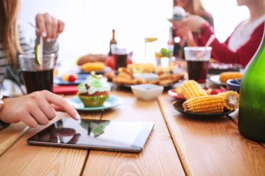 Ahşap masada otururken birlikte yemek yiyen bir grup insanın üst düzey görüntüsü. Masada yemek var. İnsanlar fast food yiyor..
