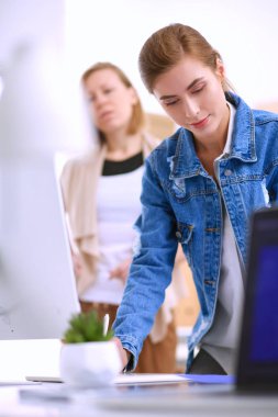 Masanın yanında duran iki genç kadın enstrüman, plan ve dizüstü bilgisayarla.