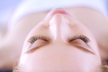 Masaj masasında uzanmış gözleri kapalı rahatlayan genç bir kadın. - Kadın. Spa salonu