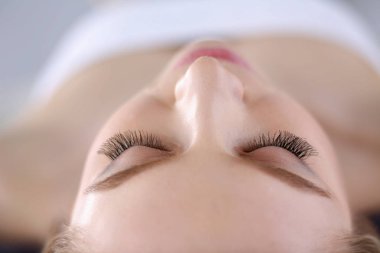 Masaj masasında uzanmış gözleri kapalı rahatlayan genç bir kadın. - Kadın. Spa salonu