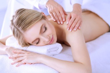 Masaj masasında uzanmış gözleri kapalı rahatlayan genç bir kadın. - Kadın. Spa salonu