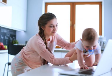 Annesi bebeğini evde parlak mutfakta ile.