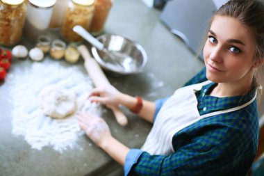 Mutfakta sobanın yanında duran genç bir kadın. .