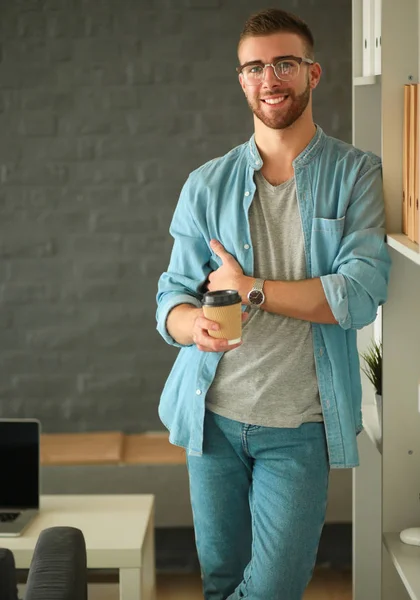 Jongeman houdt laptop staan in de buurt muur. — Stockfoto