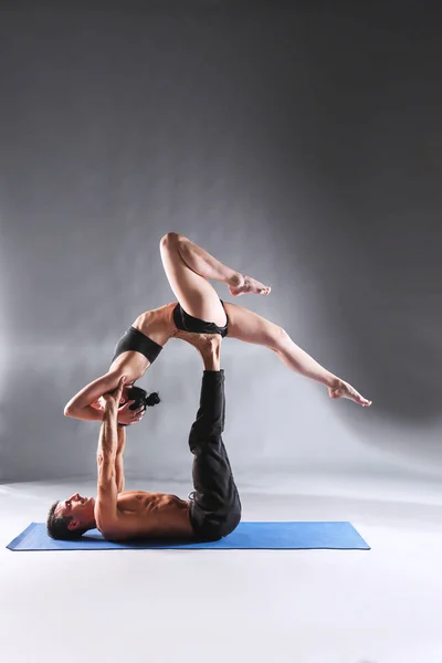 Young couple practicing acro yoga on mat in studio together. Acroyoga. Couple yoga. Partner yoga.